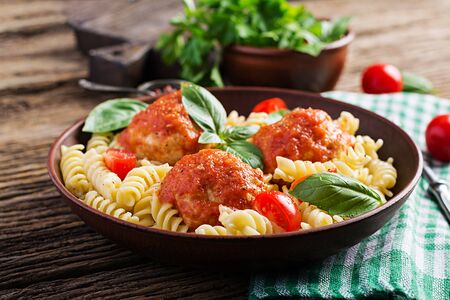Fusilli  pasta with meatballs in tomato sauce and basil in bowl. Italian cuisine.の写真素材