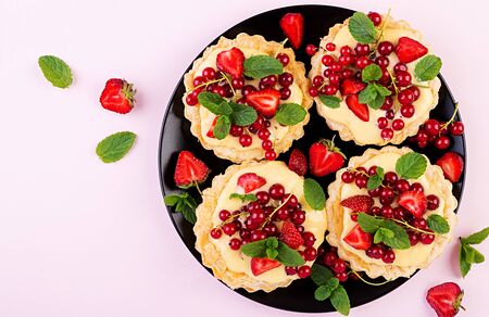 Tarts with strawberries, currant and whipped cream decorated with mint leaves. Top viewの写真素材