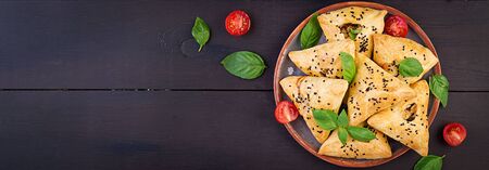 Asian food. Samsa (samosa) with chicken fillet and green herbs on wooden background. Banner. Top viewの写真素材