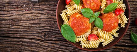 Fusilli  pasta with meatballs in tomato sauce and basil in bowl. Italian cuisine. Top view. Bannerの写真素材