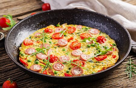 Omelette with tomatoes, sausage and green peas  in rustic style.  Frittata - italian omelet.の写真素材