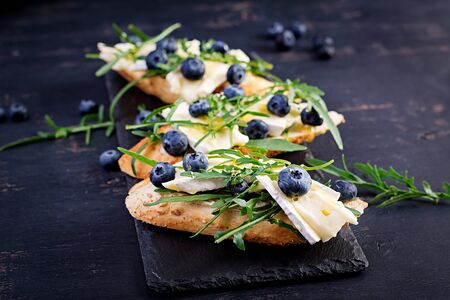 Bruschetta. Toast crostini with fresh berries blueberry and honey, brie cheese, arugula. Italian cuisineの写真素材