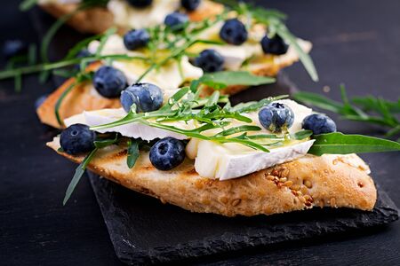 Bruschetta. Toast crostini with fresh berries blueberry and honey, brie cheese, arugula. Italian...