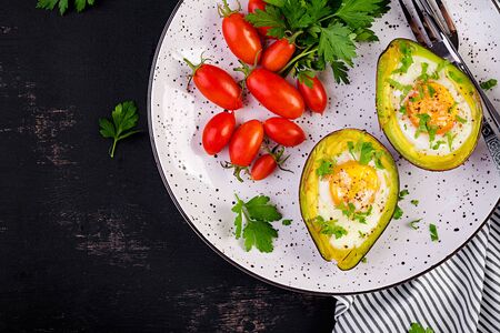 Avocado baked with egg and fresh salad. Vegetarian dish. Top view, overhead.  Ketogenic diet. Keto...