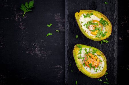 Avocado baked with egg and fresh salad. Vegetarian dish. Top view, overhead.  Ketogenic diet. Keto...