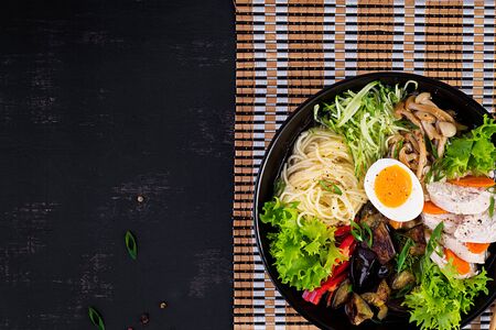 Japanese ramen soup with chicken, egg, shimeji mushrooms and eggplants on dark wooden background. Chanko nabe, sumo soup. Top viewの写真素材
