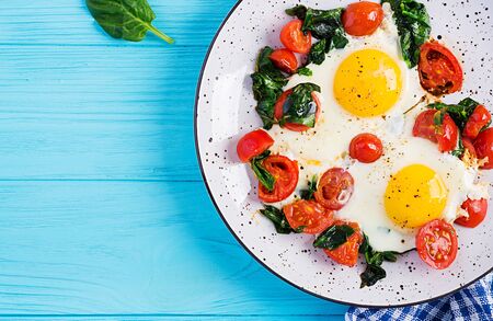 Breakfast. Ketogenic diet food. Fried egg, spinach, and tomatoes. Keto, paleo breakfast. Top view,...