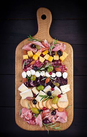 Antipasto platter with ham, prosciutto, salami, cheese,  crackers and olives on a wooden background.  Christmas table. Top view, overheadの写真素材
