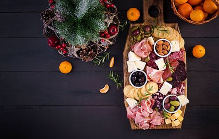 Antipasto platter with ham, prosciutto, salami, cheese,  crackers and olives on a wooden background.  Christmas table. Top view, overheadの写真素材