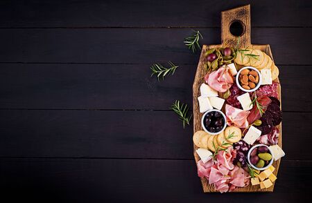 Antipasto platter with ham, prosciutto, salami, cheese,  crackers and olives on a wooden background.  Christmas table. Top view, overheadの写真素材