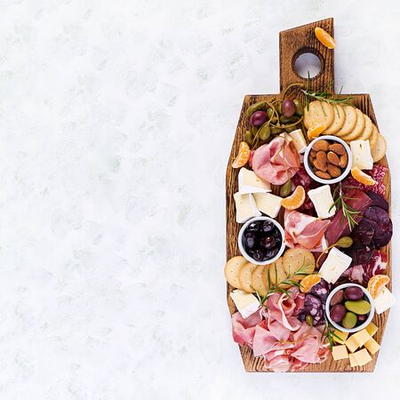 Antipasto platter with ham, prosciutto, salami, cheese,  crackers and olives on a light background.  Christmas table. Top view, overheadの写真素材