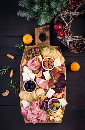 Antipasto platter with ham, prosciutto, salami, cheese,  crackers and olives on a wooden background.  Christmas table. Top view, overheadの写真素材