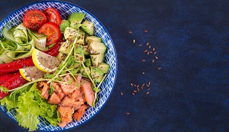 Healthy grilled salmon, avocado, tomato, cucumber, paprika and chia seeds. Balanced lunch in blue bowl. Buddha bowl. Top view, flat layの写真素材