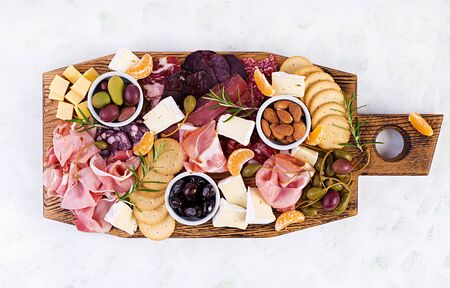 Antipasto platter with ham, prosciutto, salami, cheese,  crackers and olives on a light background. ...