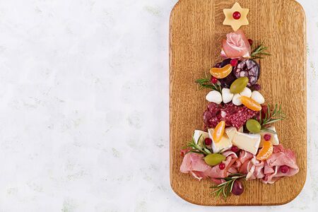 Antipasto platter with ham, prosciutto, salami, cheese,  crackers and olives on a light background.  Christmas table. Top view, overheadの写真素材