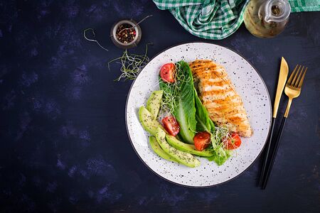 Chicken grilled fillet with salad fresh tomatoes and avocado. Healthy food, ketogenic diet, diet lunch concept. Keto/Paleo diet menu. Top view, flat layの写真素材