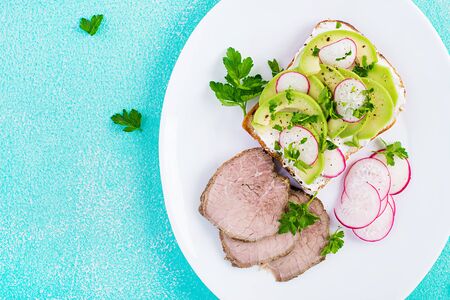 Tasty breakfast. Healthy avocado toast and radish on whole grain bread and baked sliced meat. Top view, overheadの写真素材