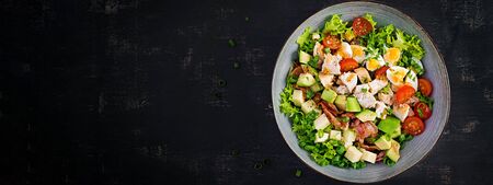 Healthy cobb salad with chicken, avocado, bacon, tomato, cheese and eggs. American food. Top view. Flat lay, bannerの写真素材
