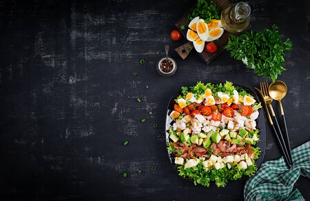 Healthy cobb salad with chicken, avocado, bacon, tomato, cheese and eggs. American food. Top view. Flat lay, overheadの写真素材