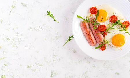 English breakfast - fried eggs, sausages, tomatoes and arugula. American food. Top view, overhead, copy spaceの写真素材