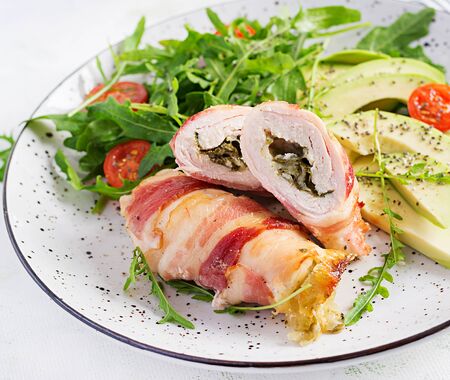 Ketogenic diet. Dinner dish with chicken meat roll wish  bacon, avocado, tomatoes and arugula. Detox and healthy concept. Keto food.の写真素材