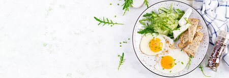 English breakfast - fried eggs, feta cheese, cucumber and arugula. American food. Top view, overhead, bannerの写真素材