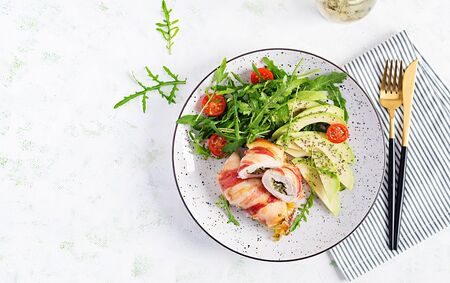 Ketogenic diet. Dinner dish with chicken meat roll wish  bacon, avocado, tomatoes and arugula. Detox and healthy concept. Keto food. Overhead, top view, flat layの写真素材