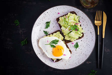 Healthy breakfast. Sandwich with avocado guacamole, cucumber and fried egg, for healthy breakfast or...