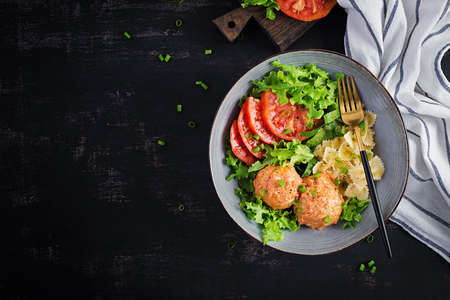 Italian pasta. Farfalle with meatballs and salad on dark background. Dinner. Top view, overhead. Slow food conceptの写真素材