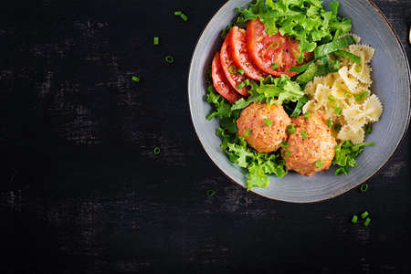 Italian pasta. Farfalle with meatballs and salad on dark background. Dinner. Top view, overhead....