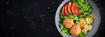 Italian pasta. Farfalle with meatballs and salad on dark background. Dinner. Top view, overhead. Banner. Slow food conceptの写真素材
