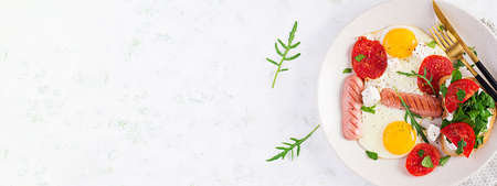 English breakfast - fried eggs, sausages, tomatoes and feta cheese. American food. Top view, overhead, bannerの写真素材