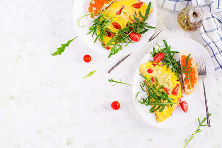 Omelette with tomatoes, cheese, ham and sandwich wich red cavier on plate. Frittata - italian...