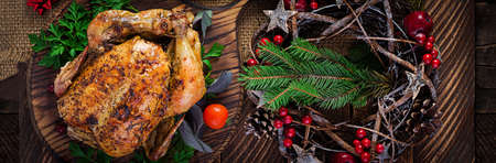Baked turkey or chicken. The Christmas table is served with a turkey, decorated with bright tinsel. Fried chicken, table setting. Christmas dinner. Top view, banner, copy spaceの写真素材