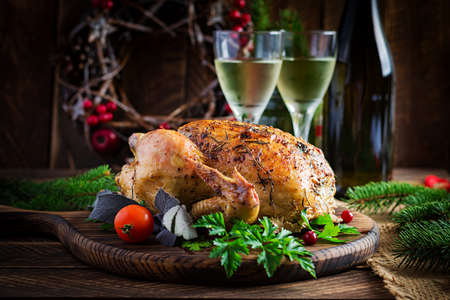Baked turkey or chicken. The Christmas table is served with a turkey, decorated with bright tinsel. Fried chicken, table setting. Christmas dinner.の写真素材
