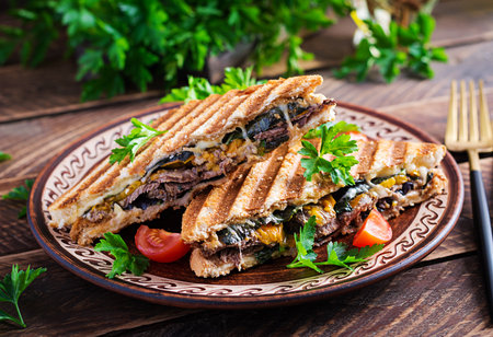 Grilled club sandwich panini with beaf, tomato, cheese and leaf mustard. Delicious breakfast or snack.の写真素材