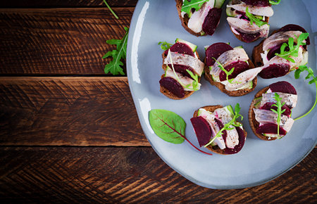 Herring fillet. Sandwich with salted herring and slice beetroot on the toasts on wooden table. Scandinavian cuisine. Top view, overheadの写真素材