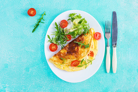 Breakfast. Omelette with tomatoes, cheese and arugula on white plate. Frittata - italian omelet....