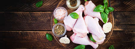 Raw chicken drumsticks with spices. Raw chicken legs with spices on a wooden background. Top view, banner, copy space.の写真素材