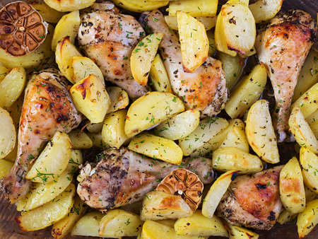 Baked chicken legs with sliced potatoes and herbs. Barbecue chicken drumsticks. Top view, overhead,...