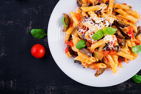 Pasta penne with eggplant. Pasta alla norma - traditional Italian food with eggplant, tomato, ricotta cheese and basil. Top view, overhead, copy spaceの写真素材