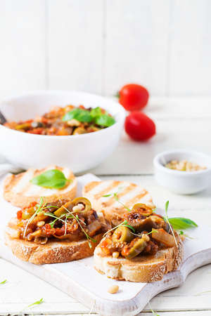 Traditional Italian Caponata and toast on a wooden white table. Sicilian caponata.の写真素材