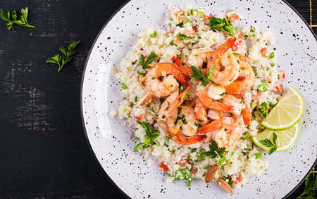 Couscous with roasted shrimps, tomatoes, red onions, almond nuts and parsley. Moroccan food with couscous and prawns. Top view, flat layの写真素材