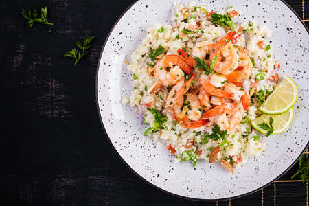 Couscous with roasted shrimps, tomatoes, red onions, almond nuts and parsley. Moroccan food with couscous and prawns. Top view, flat layの写真素材