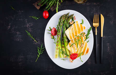 Grilled halloumi cheese salad with tomatoes and asparagus on plate on dark background. Healthy vegetarian food. Top view, aboveの写真素材