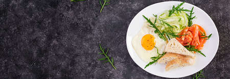 Diet breakfast. Salt salmon salad with greens, cucumbers, fried egg and bread. Top view, overhead,...