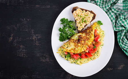 Breakfast. Omelette with zucchini, cheese and tomatoes salad with sandwich on white plate. Frittata...