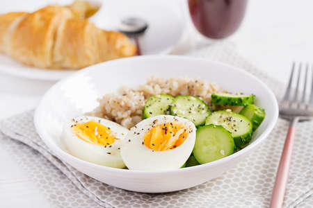 Breakfast oatmeal porridge with boiled egg, cucumber and sesame seed. Healthy balanced food.の写真素材