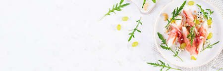 Appetizer with pear, blue cheese and prosciutto ham for holidays on a white plate. Top view, banner, flat layの写真素材