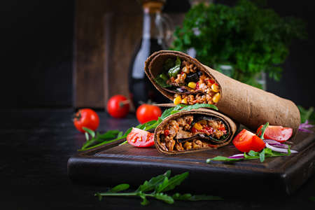 Burritos wraps with beef and vegetables on  dark wooden background. Beef burrito, mexican food.の写真素材